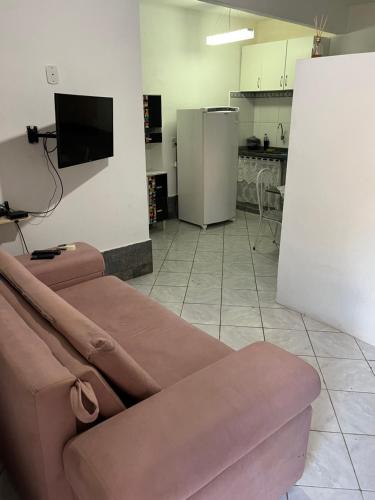 a living room with a couch and a tv at Flat em Búzios com ar in Búzios