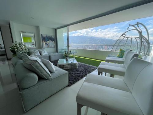 a living room with white furniture and a large window at PENHOUSE (40 Floor) to enjoy the VIEW OF THE CITY! in Itagüí