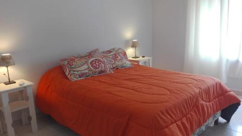 1 dormitorio con 1 cama roja, 2 mesas y 2 lámparas en Alma de Campo en San Rafael