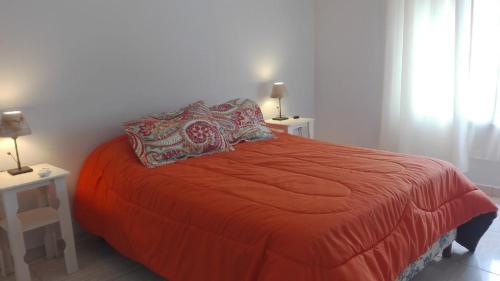 1 dormitorio con 1 cama roja, 2 mesas y 2 lámparas en Alma de Campo, en San Rafael