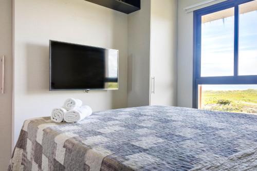 a bedroom with a bed with towels and a flat screen tv at VG Sun Cumbuco Sea Breeze Vista Mar in Cumbuco