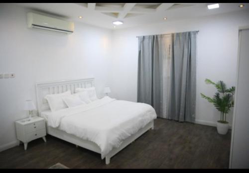 a bedroom with a white bed and a potted plant at شقة جديدة ومفروشة للايجار اليومي والشهري في محافظة الرس in Ar Rass