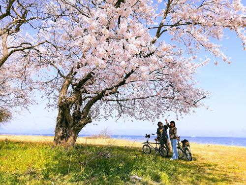 due persone in piedi sotto un albero con le loro biciclette di 静かに過ごす室内テント Staying quietly indoor tent a Takashima