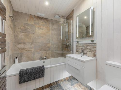 a white bathroom with a tub and a sink at Heather Lodge in Willington