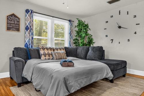 ein Wohnzimmer mit einer Couch und einer Uhr an der Wand in der Unterkunft Orlando Oasis! Free Laundry & Parking Near Disney! in Orlando