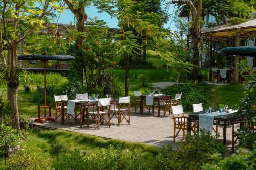 a patio with tables and chairs in a garden at aNhill Boutique in Hue