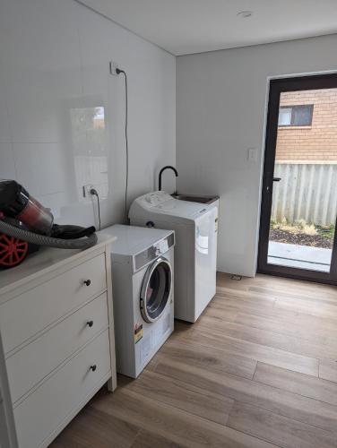 a laundry room with a washing machine and a washer at Golden Bay Beach House in Secret Harbour