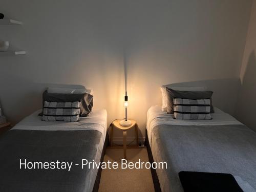 Homestay - Yarra River Boulevard في ملبورن: سريرين توأم في غرفة بها مصباح