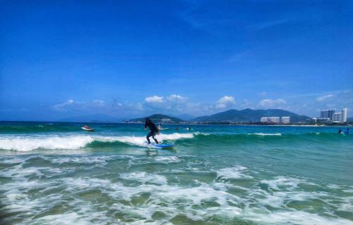una persona montando una ola en una tabla de surf en el océano en Wan Ning Xiao Gang Guest House, en Wanning