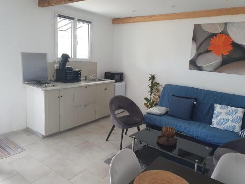 a living room with a blue couch and a kitchen at appartement in Marmande