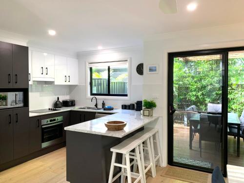 a kitchen with black and white cabinets and a table at The Place - Culburra Beach in Culburra Beach