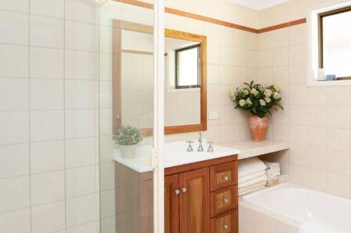 ein Badezimmer mit einem Waschbecken, einer Badewanne und einem Spiegel in der Unterkunft Martha's ......... Your hideaway in the highlands. in Burradoo