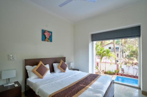 um quarto com uma cama grande e uma janela grande em 4BHK Luxury Villa with Private Pool Near Candolim em Marmagao
