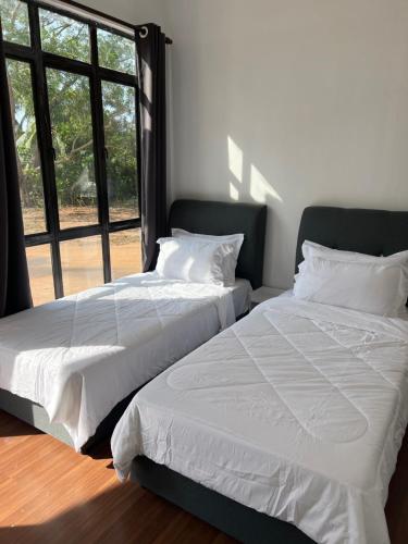 twee bedden naast elkaar in een slaapkamer bij A’Casa Cottage in Kuala Terengganu