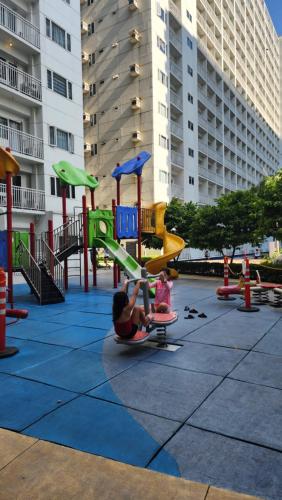 uma mulher e uma criança a brincar num parque infantil em EZStays Shore Residences em Manila