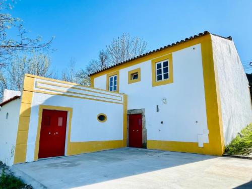 a large white and yellow house with red doors at Casa do Martinho in Castelo de Vide