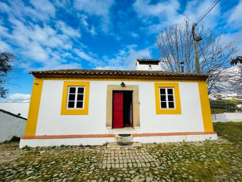 una pequeña casa blanca y amarilla con puerta roja en Casa do Martinho, en Castelo de Vide