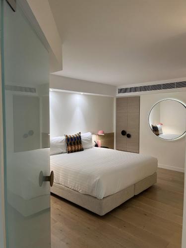 a bedroom with a white bed and a mirror at Miss Baker's Boutique Accommodation Bondi in Sydney