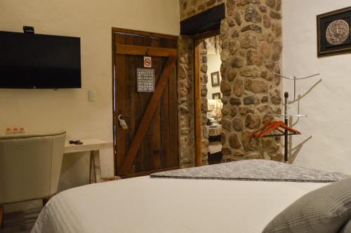 a room with a bed and a door with a television at Hotel de Piedra in Bernal