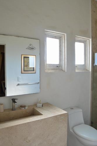 a bathroom with a sink and a toilet and two windows at Hotel de Piedra in Bernal