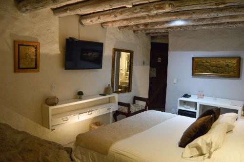 a bedroom with a bed and a tv on the wall at Hotel de Piedra in Bernal