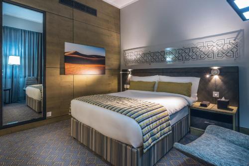 a hotel room with a large bed and a desk at Ayla Bawadi Hotel & Mall in Al Ain