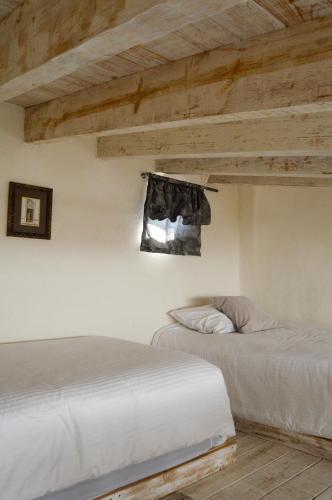 two beds in a room with wooden ceilings at Hotel de Piedra in Bernal