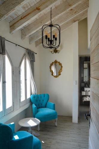 a living room with a blue chair and a chandelier at Hotel de Piedra in Bernal