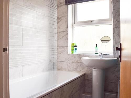 ein Bad mit einem Waschbecken, einer Badewanne und einem Fenster in der Unterkunft Sidelands Sojourn in Stratford-upon-Avon