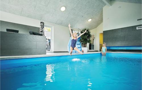 Una donna che salta in una piscina di Lovely Home In Frederiksvrk With Indoor Swimming Pool a Melby