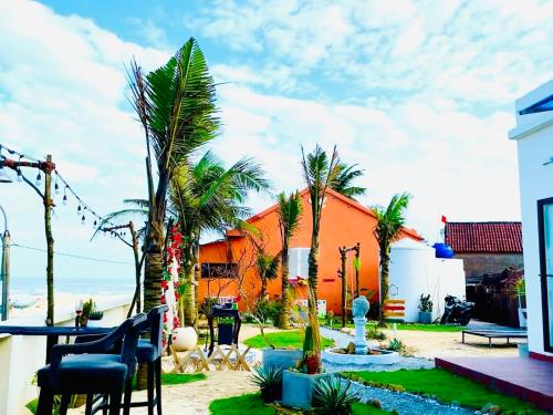 un patio avec des palmiers et un bâtiment orange dans l'établissement JEJU Beach Front Villa, à Tam Kỳ