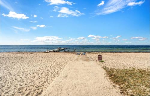 a sandy beach with a pier and the ocean at Awesome Home In Tranekær in Tranekær