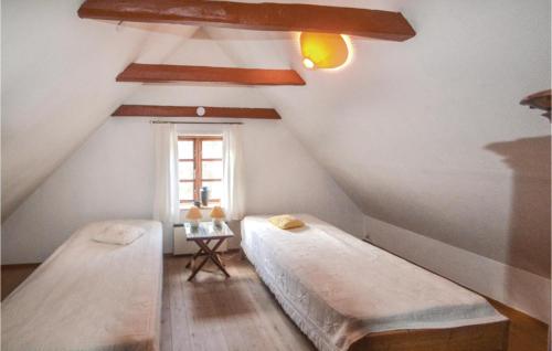 Cette chambre mansardée comprend 2 lits et une fenêtre. dans l'établissement Nice Home In rsted With 3 Bedrooms And Wifi, à Udbyhøj