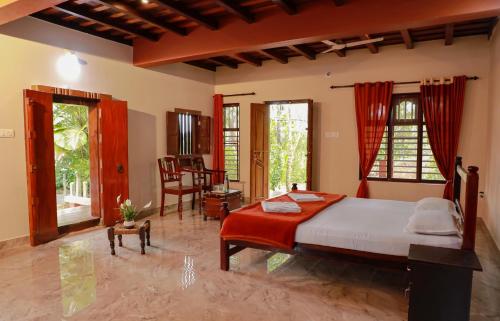 a bedroom with a bed and a desk and windows at Kudajadri Heritage Homestay in Kaniyāmbetta