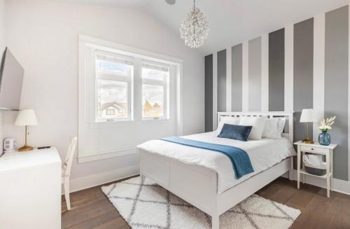 a white bedroom with a bed and a window at Vancouver West Cozy Retreat by Host Launch in Vancouver