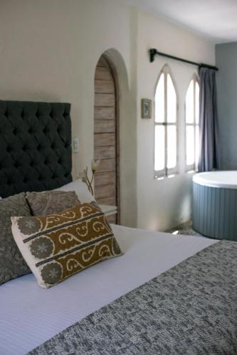 a bedroom with a bed and a window and a tub at Hotel de Piedra in Bernal