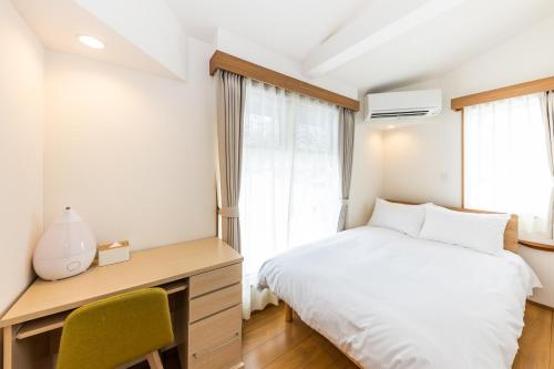 1 dormitorio con cama, escritorio y ventana en HOPETREE CoCo HAPPO TOWNS, en Hakuba