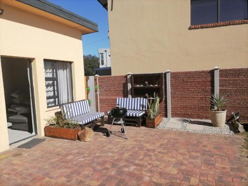 a patio with two chairs and a grill next to a building at @Kitchens in Jeffreys Bay