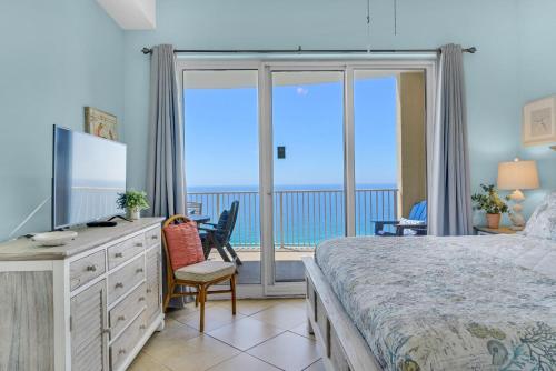 um quarto com uma cama, uma televisão e uma varanda em Ocean Villa Penthouse #2302 em Panama City Beach