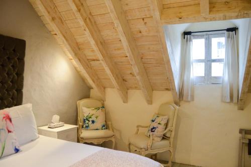 a bedroom with two chairs and a bed and a window at Hotel de Piedra in Bernal