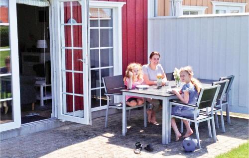 a woman and two little girls sitting at a table at Holiday Home Strandg in Bro