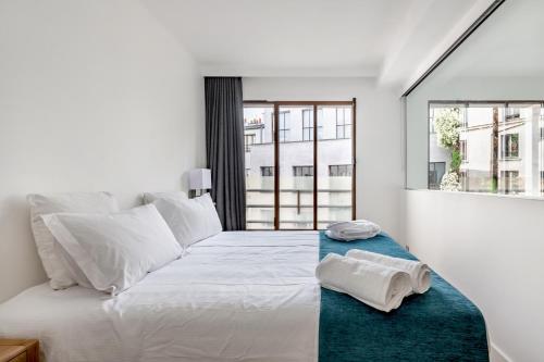 a white bedroom with a large bed with towels on it at LOFT A BASTILLE in Paris