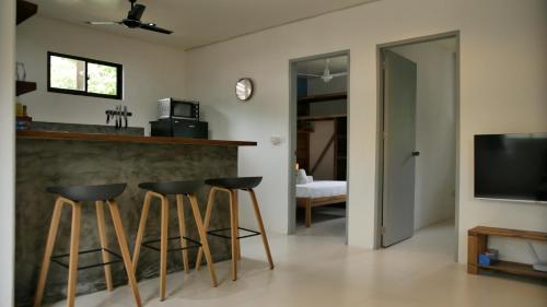 a living room with a bar with stools and a television at Calao Villa, Solar Villa 2 rooms with Private Pool in El Nido