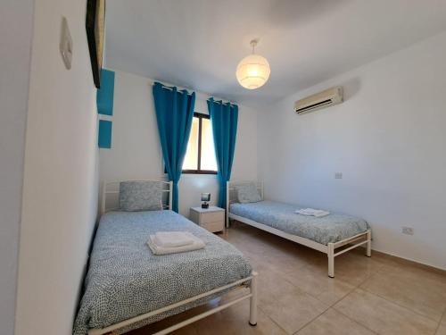 a bedroom with two beds and blue curtains at Afroditi Apartment in Perivolia