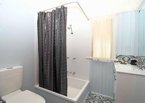 a bathroom with a toilet and a shower curtain at Family Tides in Urangan