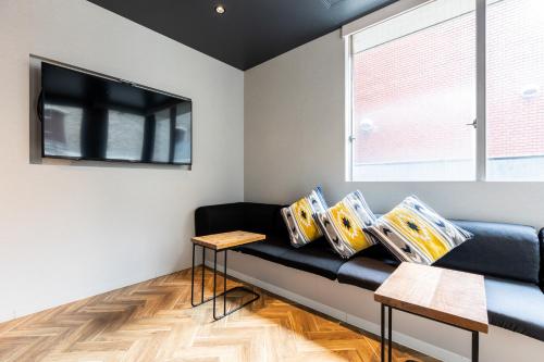 a living room with a black couch and a window at Akasaka The Hostel in Tokyo