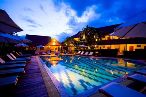 a large swimming pool with lounge chairs next to a building at Karinthip Village in Chiang Mai