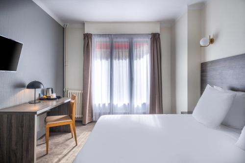 a hotel room with a bed and a desk and a window at Sure Hotel By Best Western Lorient Centre in Lorient
