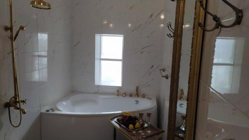 a white bathroom with a tub and a window at Jumpravas pils in Jumprava