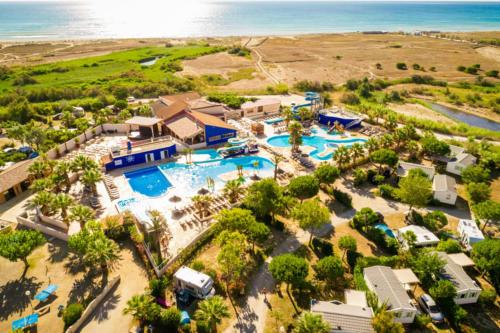 une vue aérienne d'un complexe hôtelier avec piscine et l'océan dans l'établissement Camping Officiel Siblu Le Marisol, à Torreilles